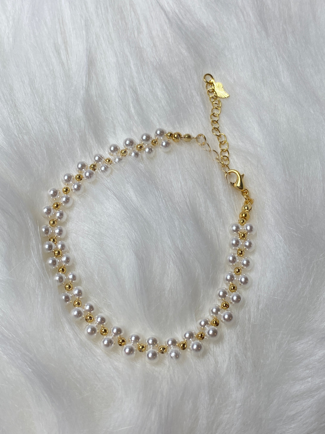  handmade bracelet featuring pearl-style glass beads and gold accents, designed with an adjustable chain for a comfortable and elegant fit.