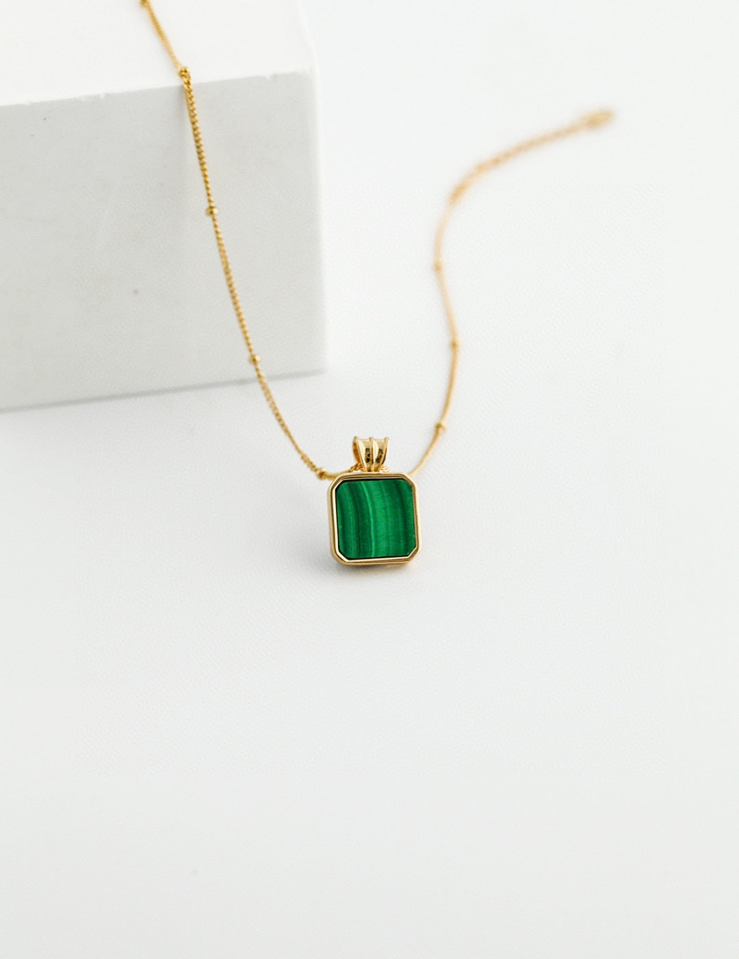 Gold vermeil necklace with a square malachite pendant, showcasing a rich green stone known for its transformative properties.