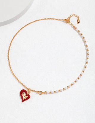 the unique combination of a classic pearl strand and a sleek chain, linked together with a heart-shaped red enamel pendant 